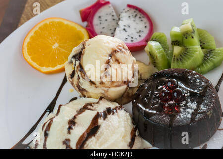 Gâteau au chocolat servi avec set de lave glace vanille crème,essuya et mélanger les fruits sur plaque blanche,couleur Banque D'Images