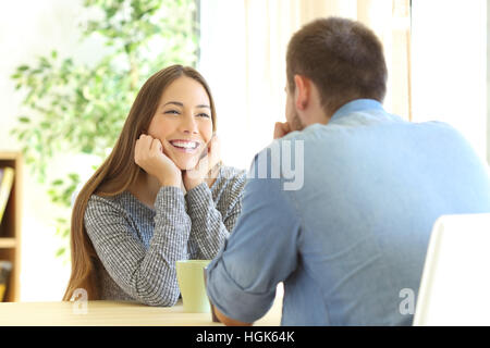 Fille romantique tomber en amour dans une première date assis dans une table dans la salle de séjour à la maison Banque D'Images