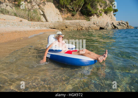 Senior en vacances flottant à la présidence dans la mer Banque D'Images