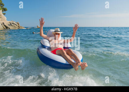 Senior en vacances flottant à la présidence dans la mer Banque D'Images