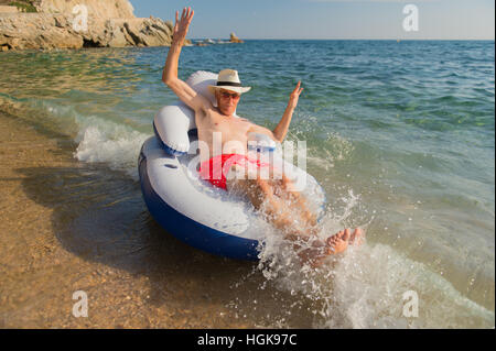 Senior en vacances flottant à la présidence dans la mer Banque D'Images