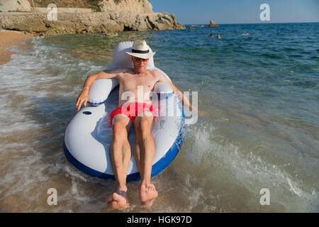 Senior en vacances flottant à la présidence dans la mer Banque D'Images