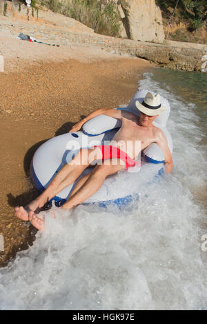 Senior en vacances flottant à la présidence dans la mer Banque D'Images