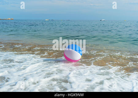Ballon de plage gonflable coloré jouant avec le surf et la mer Banque D'Images