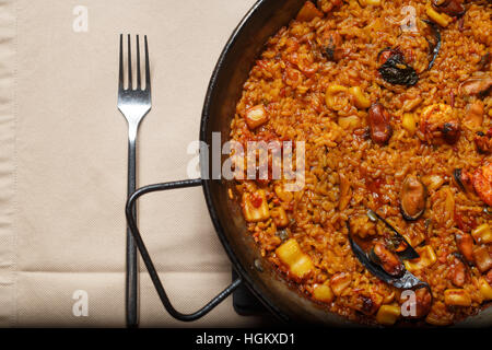 Paella dans un moule en métal tourné avec lumière artificielle Banque D'Images