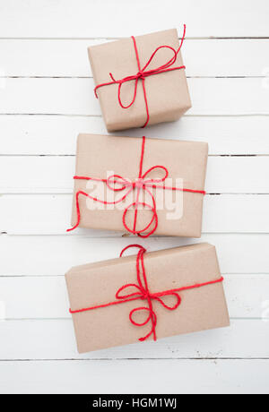 Noël brun rustique paquet papier attachés avec des chaînes. Fond de bois blanc. Banque D'Images