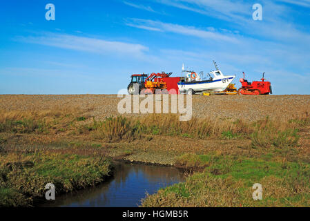 Bateaux de pêche côtière et les tracteurs échoué sur les galets à la crête de la mer suivant le CLAJ, Norfolk, Angleterre, Royaume-Uni. Banque D'Images