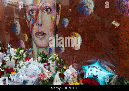 Londres, Royaume-Uni. 10 janvier 2017. Fans de recueillir par l'œuvre de David Bowie dans la maison natale de l'artiste de Brixton pour commémorer le premier anniversaire de la mort du musicien. La murale Brixton qui dépeint le visage de Bowie d'Aladdin Sane couverture de l'album devient le principal lieu de mémoire après la mort de l'étoile le 10 janvier 2016. Wiktor Szymanowicz/Alamy Live News Banque D'Images