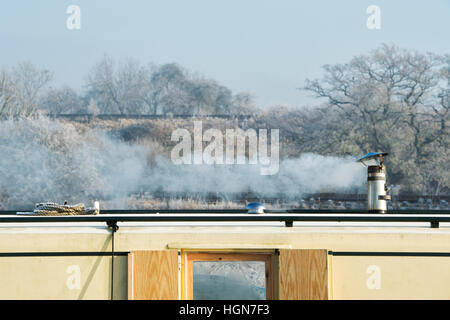 Canal Boat cheminée et de la fumée sur un matin glacial de décembre. Aynho, Banbury, Oxfordshire, Angleterre Banque D'Images