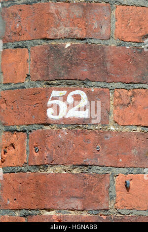 Numéro de maison 52 sign on peint en blanc sur le mur de brique rouge Banque D'Images