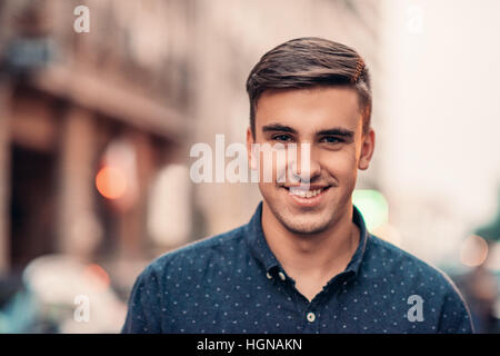 Beau jeune homme souriant sur une rue de la ville Banque D'Images
