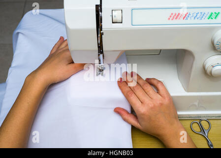 Woman's hands travaillant sur machine à coudre. Noir et blanc. couturière coudre un tissu blanc Banque D'Images