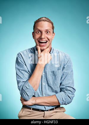 Heureux excite young man smiling sur fond bleu Banque D'Images