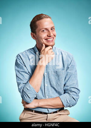 Heureux excite young man smiling sur fond bleu Banque D'Images