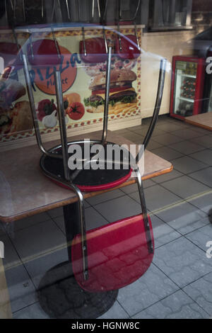 À la fermeture dans un restaurant avec la pluie sur la fenêtre et vide de tables et de chaises. Banque D'Images