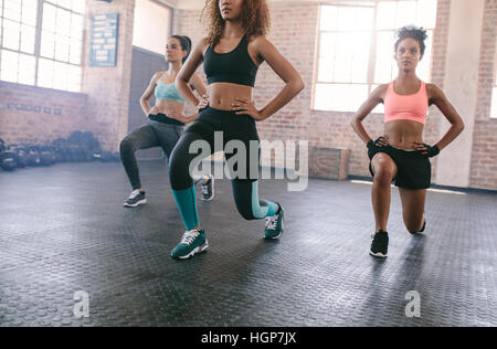 Portrait de trois jeunes femmes faisant l'entraînement ensemble dans une salle de sport. Les femmes exerçant en cours de conditionnement physique. Banque D'Images