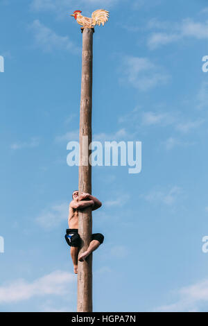 Gomel, Bélarus - Mars 12, 2016 : Jeune homme grimpe sur un poste en bois sur les traditionnelles fêtes de dédié à l'approche du printemps - célébration slaves Banque D'Images