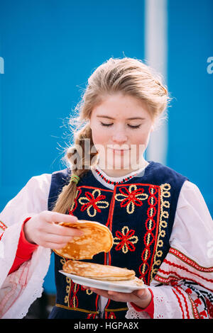 Gomel, Bélarus - 12 mars 2016 : Pas de belle jeune femme fille en vêtements folklorique national tente sur le goût des crêpes lors de célébration de Maslenitsa Shr Banque D'Images