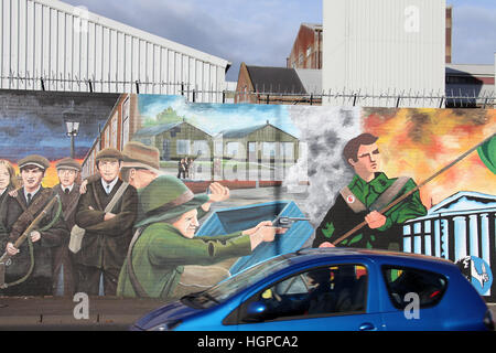 Voiture roulant vers le bas la Falls Road à Belfast passé le mur de la paix internationale Banque D'Images