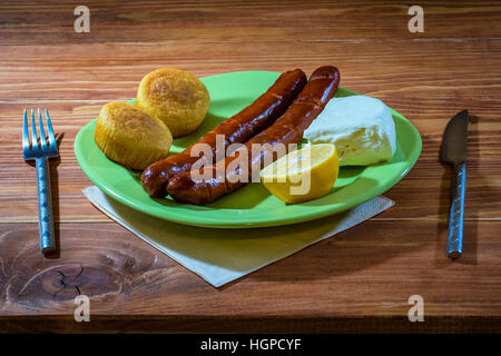 Saucisses grillées avec du pain de maïs et le fromage blanc servi dans une assiette sur une table en bois Banque D'Images