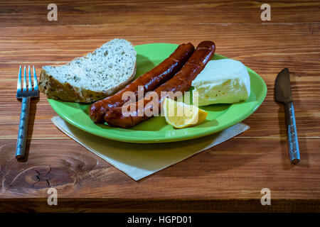 Saucisses grillées avec du pain de maïs et le fromage blanc servi dans une assiette sur une table en bois Banque D'Images