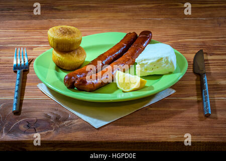 Saucisses grillées avec du pain de maïs et le fromage blanc servi dans une assiette sur une table en bois Banque D'Images