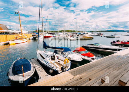 Oslo, Norvège. La jetée en bois sur la mer avec des bateaux amarrés et yachts au quartier Aker Brygge. Le paysage marin de Port et quais en été journée ensoleillée dans le sc Banque D'Images
