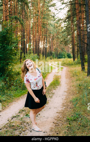 Très jolie grande taille Happy Smiling Woman Laughing Girl Femme avec de longs cheveux bruns ondulés en T-Shirt blanc et noir jupe courte Article Full-Leng Banque D'Images
