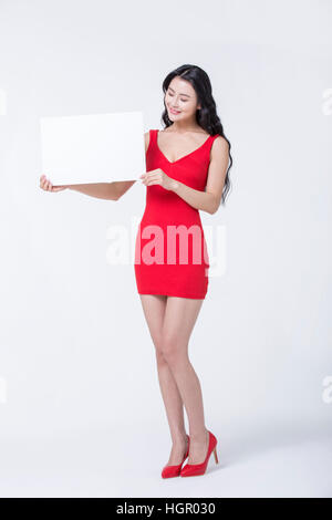 Young smiling slim woman in red dress montrant un conseil Banque D'Images