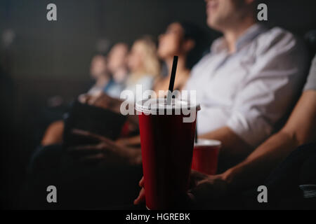 Gros plan des jeunes avec des boissons non alcoolisées dans un cinéma, l'accent sur verre froid. Banque D'Images