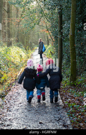 Mère et 3 enfants Trois enfants filles / marche à pied le long du chemin boueux / dans la boue sur la voie de chemin de ronde pied sentier Esher UK Banque D'Images