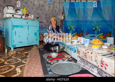 La préparation de la femme nomade kazakh table pour invités dans une yourte, Ile-Alatau Parc National, Assy Plateau, Almaty, Kazakhstan Banque D'Images