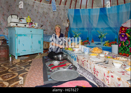 La préparation de la femme nomade kazakh table pour invités dans une yourte, Ile-Alatau Parc National, Assy Plateau, Almaty, Kazakhstan Banque D'Images