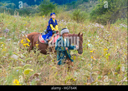 Balades autour de l'homme kazakh avec son fils sur un cheval après la cérémonie de circoncision Sundet Toi, Kazakh village ethnographique Banque D'Images