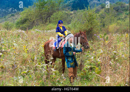 Balades autour de l'homme kazakh avec son fils sur un cheval après la cérémonie de circoncision Sundet Toi, Kazakh village ethnographique Banque D'Images