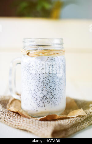 Semences Chia pudding dans un pot blanc sur fond de bois Banque D'Images