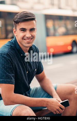 Jeune homme assis sur un banc dans la ville Banque D'Images