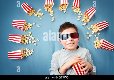 Enfant couché sur fond bleu dans les lunettes 3d et regarder la télévision Banque D'Images