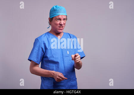 Un homme d'âge moyen en colère doctor standing in a blue scrubs et crier Banque D'Images