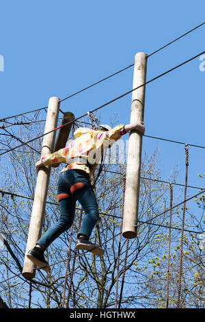 La jeune fille gravit les obstacles de parc en claire journée d'été Banque D'Images