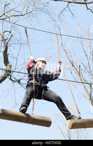 La jeune fille gravit les obstacles de parc en claire journée d'été Banque D'Images