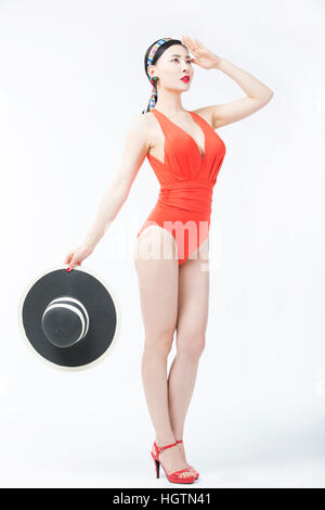 Vue latérale du jeune femme en maillot orange posing holding a hat Banque D'Images