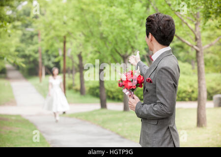 Vue latérale du jeune marié avec des fleurs pour mariée en attente à l'extérieur Banque D'Images