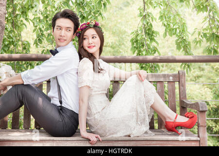 Jeune couple de mariage romantique sur un banc à l'extérieur Banque D'Images