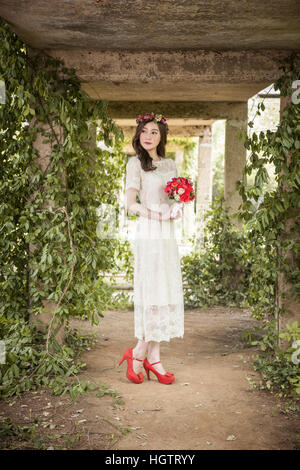 Jeune mariée avec fleurs standing outdoors Banque D'Images