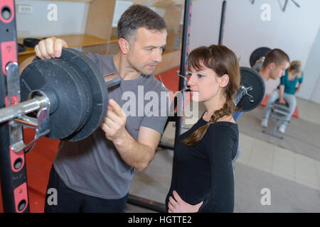 Formateur en expliquant comment utiliser une machine dans une salle de sport Banque D'Images