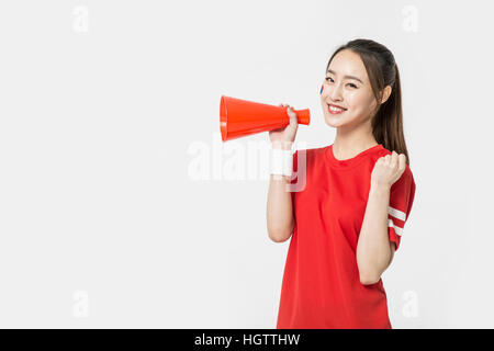 Side view of young smiling woman holding a megaphone cheerleader Banque D'Images