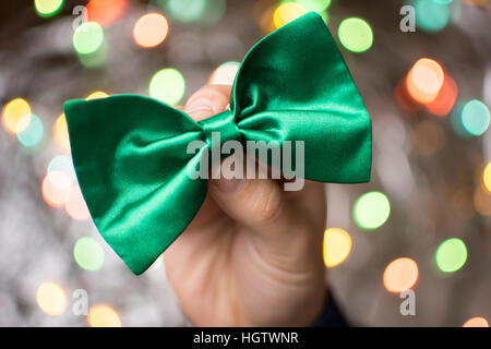 Male hand holding a green Bow tie. Préparation St Patricks day Banque D'Images