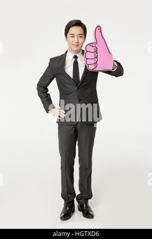 Young smiling businessman cheering avec thumb-up Connexion Banque D'Images