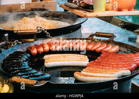 Les pommes de terre et de saucisses frits sur une poêle. Le plat traditionnel de Noël de l'alimentation de rue sur les rues de l'Europe en hiver pendant les vacances de Noël. Banque D'Images